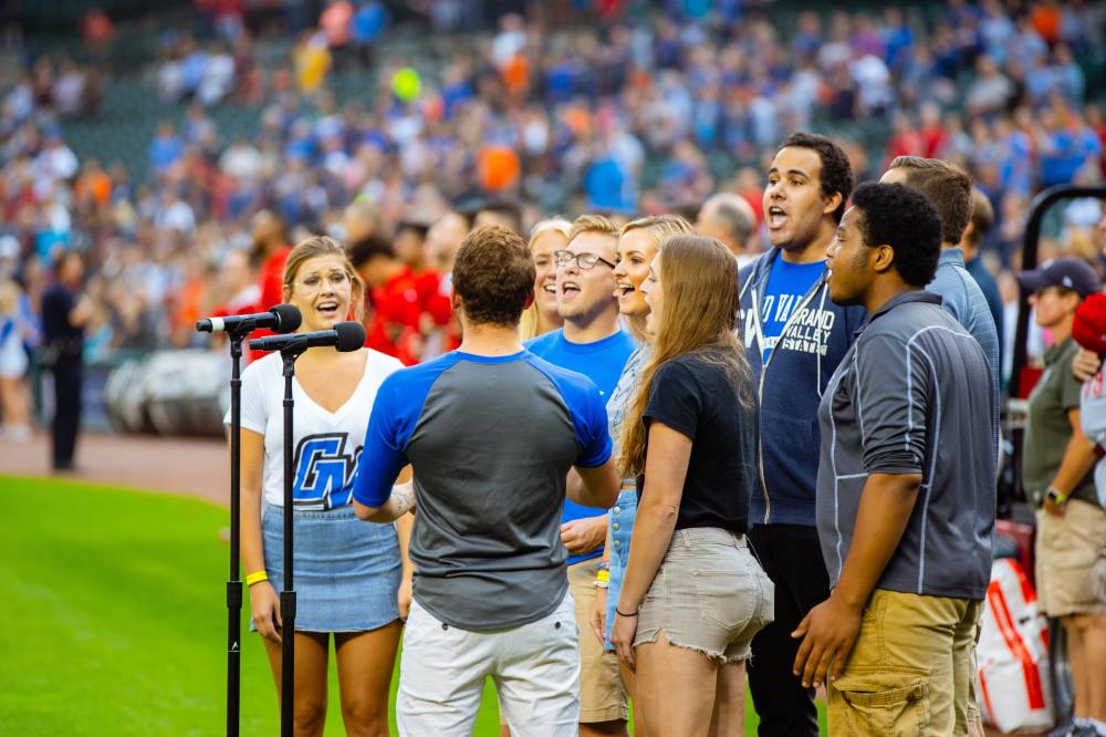 A group of gvsu choir students singing the national anthem to start the tigers game